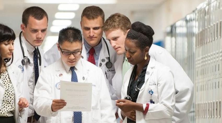 一群不同的医科学生凑在一起阅读一份文件。